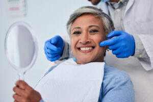 Happy senior woman, dentist pointing at her teeth.