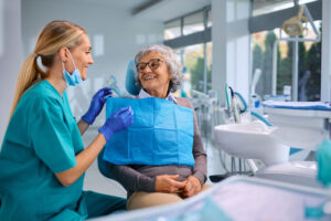 Happy elderly woman talking to her orthodontist during appointment at dentist's office. Discussing treatment process.